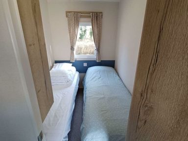 a small bedroom with two beds and a window at Hafan y Mor Haven - Holiday Accommodation 12637 Pwllheli