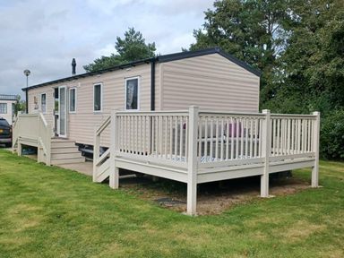 a mobile home with a deck and grassy area at Hafan y Mor Haven - Holiday Accommodation 12637 in Pwllheli