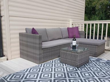 a seating area with a gray sectional sofa and glass coffee table on a patterned rug at Hafan y Mor Haven - Holiday Accommodation 12637 Pwllheli