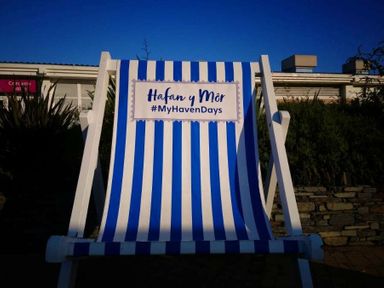 a deck chair with blue and white stripes and a sign reading 'Hafan y Môr #MyHavenDays' at Hafan y Mor Haven - Holiday Accommodation 12637 in Pwllheli