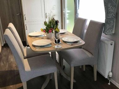 a dining table set with plates and a bottle on display at Kelling Heath Holiday Park - Holiday Accommodation 13133, Holt
