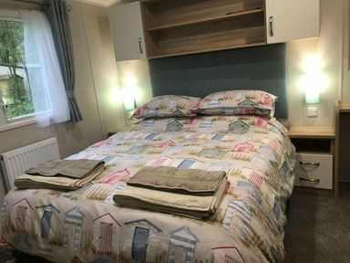 a bedroom with a double bed covered in a patterned quilt at Kelling Heath Holiday Park - Holiday Accommodation 13133, Holt
