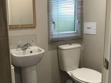 a small bathroom with a sink, toilet, and window at Kelling Heath Holiday Park - Holiday Accommodation 13133, Holt