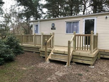 a wooden deck with steps leading to a holiday home at Kelling Heath Holiday Park - Holiday Accommodation 13133 in Holt