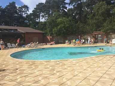 an outdoor swimming pool with people sunbathing and swimming at Kelling Heath Holiday Park - Holiday Accommodation 13133 in Holt