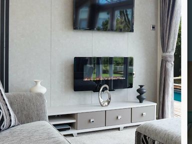 a living room with a television and fireplace on the wall at Ocean Edge Leisure Park - Holiday Accommodation 1317, Heysham