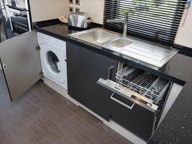 a kitchen area with a washing machine and a dishwasher under the counter at Ocean Edge Leisure Park - Holiday Accommodation 1317, Heysham