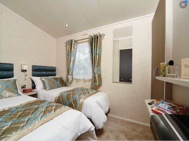 a bedroom with two twin beds, a mirror, and a small shelf at Ocean Edge Leisure Park - Holiday Accommodation 1317, Heysham