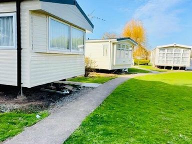two holiday caravans on a grassy area with a walkway at Butlins Minehead - Holiday Accommodation 13288 Minehead