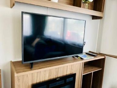 a television on a wooden entertainment unit with shelves at Butlins Minehead - Holiday Accommodation 13288 in Minehead