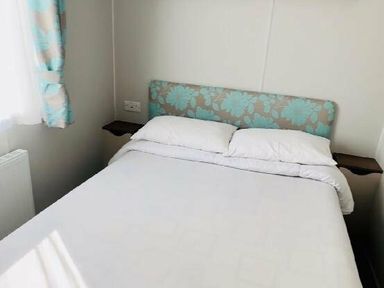 a bedroom with a bed featuring a floral headboard and white bedding at Butlins Minehead - Holiday Accommodation 13288 in Minehead