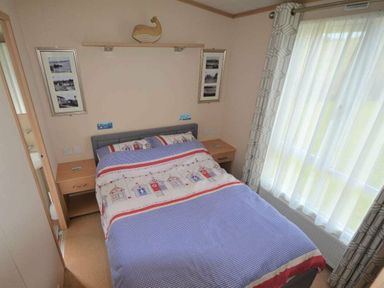 a bedroom with a bed, bedside tables, and window treatments at Perran Sands - Holiday Accommodation 15012 in Perranporth