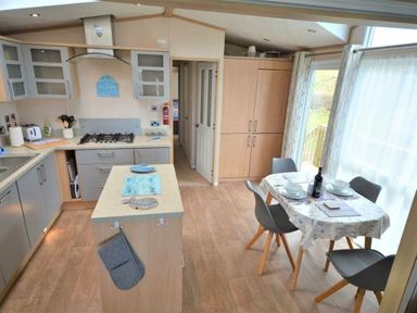 a kitchen with an island, dining table, and appliances at Perran Sands - Holiday Accommodation 15012, Perranporth