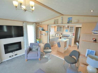 a living room with a television, sofa, and kitchen area at Perran Sands - Holiday Accommodation 15012 in Perranporth