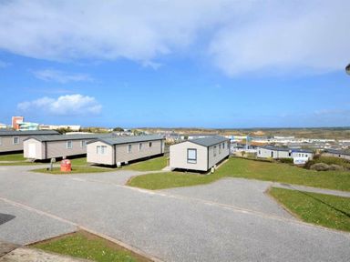 a row of holiday caravans on a grassy area with a view of the sky at Perran Sands - Holiday Accommodation 15012 in Perranporth