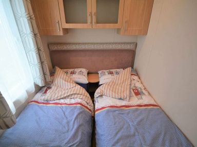 two single beds with patterned bedding and a bedside table in a cozy bedroom at Perran Sands - Holiday Accommodation 15012 in Perranporth