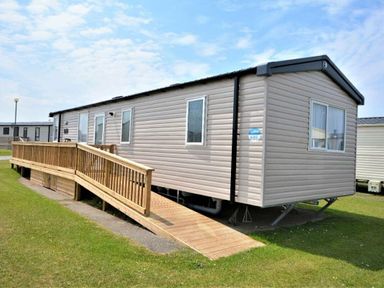a mobile home with a wooden ramp and grassy area at Perran Sands - Holiday Accommodation 15554, Perranporth