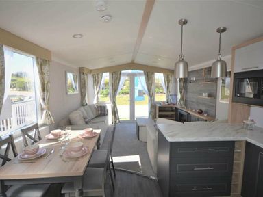 a living room and dining area with a kitchen island at Perran Sands - Holiday Accommodation 15554 in Perranporth