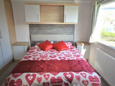 a bedroom with a bed featuring heart-patterned bedding and two bedside tables at Perran Sands - Holiday Accommodation 15554, Perranporth
