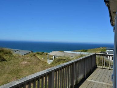 a view of the ocean from a wooden balcony at Perran Sands - Holiday Accommodation 15598 in Perranporth