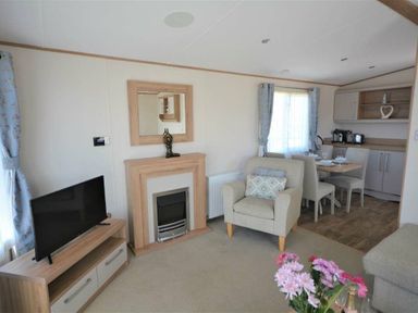 a living room with a fireplace, TV, and dining area at Perran Sands - Holiday Accommodation 15598 in Perranporth