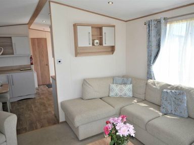 a seating area with a sofa and flowers on a table at Perran Sands - Holiday Accommodation 15598 in Perranporth