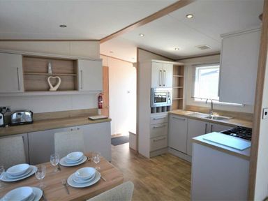 a kitchen area with dining table and chairs at Perran Sands - Holiday Accommodation 15598, Perranporth