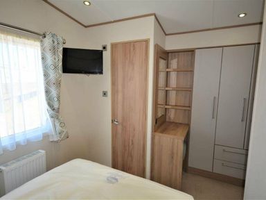 a small bedroom with a bed, a wall-mounted TV, and a built-in wardrobe at Perran Sands - Holiday Accommodation 15598, Perranporth