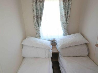 a small bedroom with two beds pushed together and pillows stacked at Perran Sands - Holiday Accommodation 15598 Perranporth