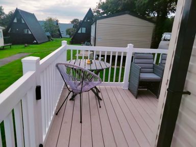 a patio with a table and chairs overlooking green grass at Hafan y Mor Haven - Holiday Accommodation 15817 in Pwllheli