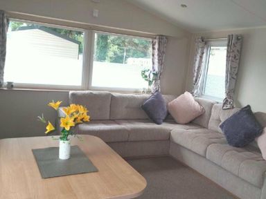 a seating area with a corner sofa and a table at Hafan y Mor Haven - Holiday Accommodation 15817 in Pwllheli