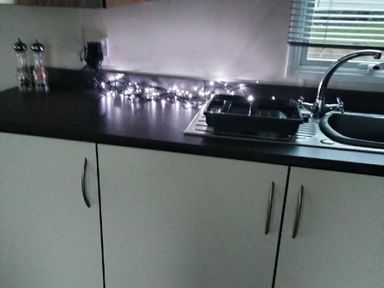 a kitchen counter with a sink, dish rack, and string lights at Hafan y Mor Haven - Holiday Accommodation 15817 Pwllheli