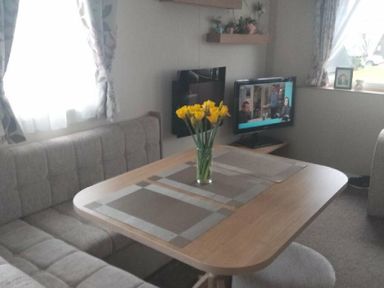 a dining area with a table and flowers at Hafan y Mor Haven - Holiday Accommodation 15817 in Pwllheli