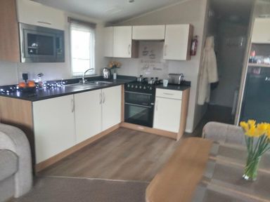 a kitchen with appliances and a dining area at Hafan y Mor Haven - Holiday Accommodation 15817 in Pwllheli