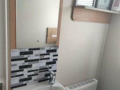 a wash basin with a mirror and tiled wall at Hafan y Mor Haven - Holiday Accommodation 15817 in Pwllheli