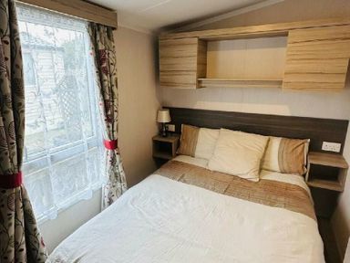 a bedroom with a double bed and a wall-mounted shelf at Unity Holiday Resort - Holiday Accommodation 15970 in Brean Sands