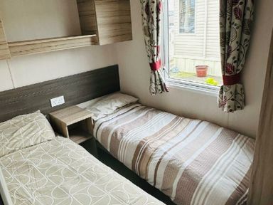 a small bedroom with two single beds and a window at Unity Holiday Resort - Holiday Accommodation 15970 Brean Sands
