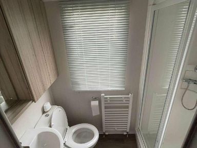 a compact bathroom with a toilet, shower, and window at Unity Holiday Resort - Holiday Accommodation 15970 in Brean Sands