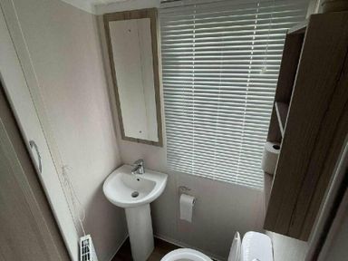 a bathroom with a sink, mirror, and shelves at Unity Holiday Resort - Holiday Accommodation 15970 in Brean Sands