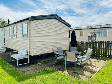 a caravan with outdoor seating and a table at Unity Holiday Resort - Holiday Accommodation 15970 Brean Sands