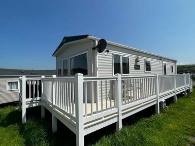 a mobile home with a deck and white railings at Newquay Bay Resort - Holiday Accommodation 15978 Newquay