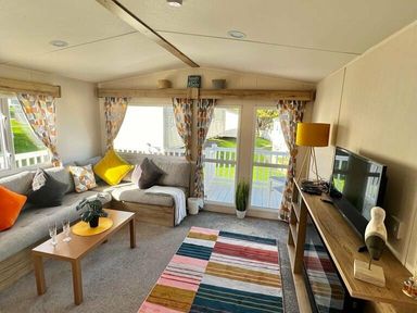 a living room with a sofa, a coffee table, and a television at Newquay Bay Resort - Holiday Accommodation 15978 in Newquay