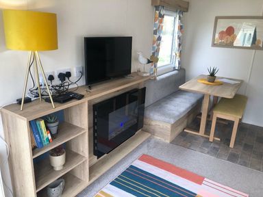 a living room with a TV, a couch, and a dining table at Newquay Bay Resort - Holiday Accommodation 15978, Newquay