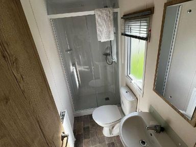 a bathroom with a shower, toilet, sink, and mirror at Newquay Bay Resort - Holiday Accommodation 15978 in Newquay
