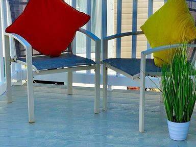 two chairs with red and yellow cushions and a plant on a deck at Newquay Bay Resort - Holiday Accommodation 15978, Newquay