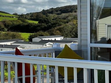 a balcony with two pillows overlooking a grassy area and caravans at Newquay Bay Resort - Holiday Accommodation 15978 in Newquay
