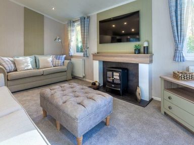 a living room with a sofa, television, a fireplace, and an ottoman at Kelling Heath Holiday Park - Holiday Accommodation 16221, Holt