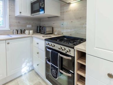 a kitchen with a gas stove, microwave, and cabinetry at Kelling Heath Holiday Park - Holiday Accommodation 16221, Holt