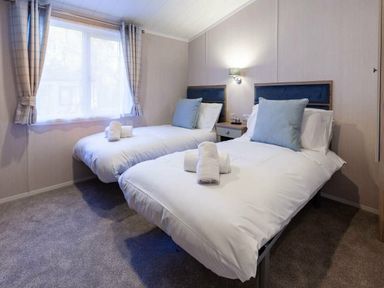 a bedroom with two single beds and towels at Kelling Heath Holiday Park - Holiday Accommodation 16221, Holt