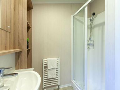 a bathroom featuring a shower, sink, towel rack, and wooden shelving at Kelling Heath Holiday Park - Holiday Accommodation 16221 in Holt